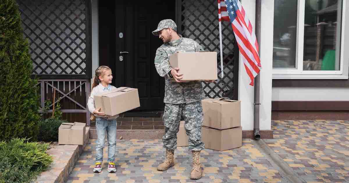 Father in military uniform and daughter holding cardboard boxes.
