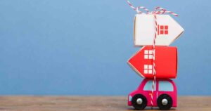 Toy car carrying a stack of houses, representing a residential mover.