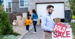 Realtor hanging sold sign, ready to work with movers in the real estate referral network.