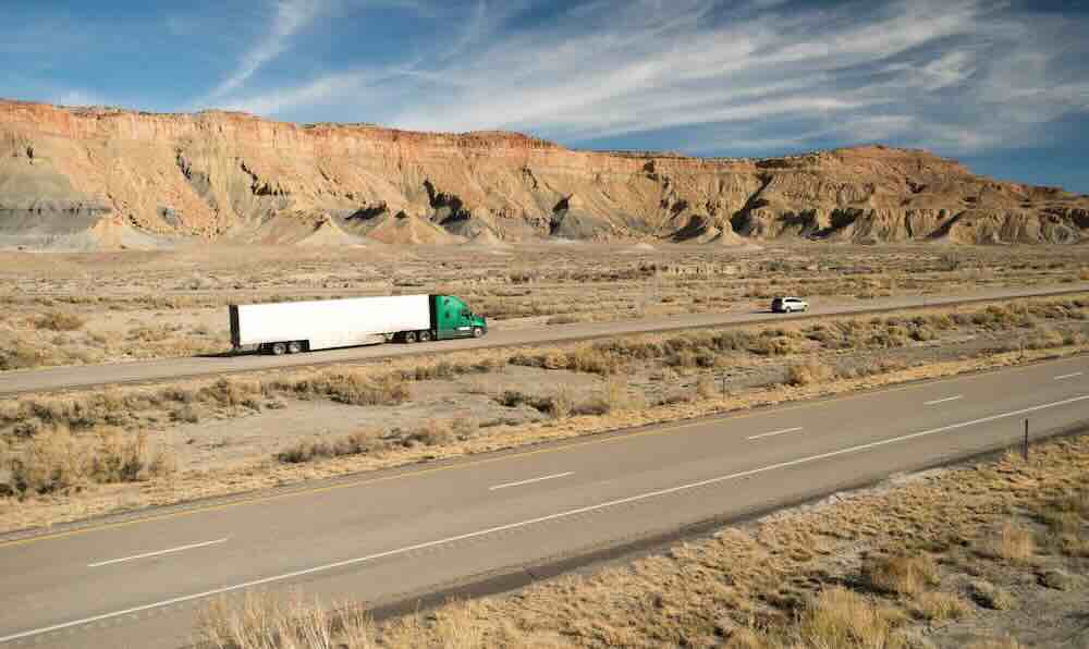 Semi-truck driving through the desert during cross-country moves.