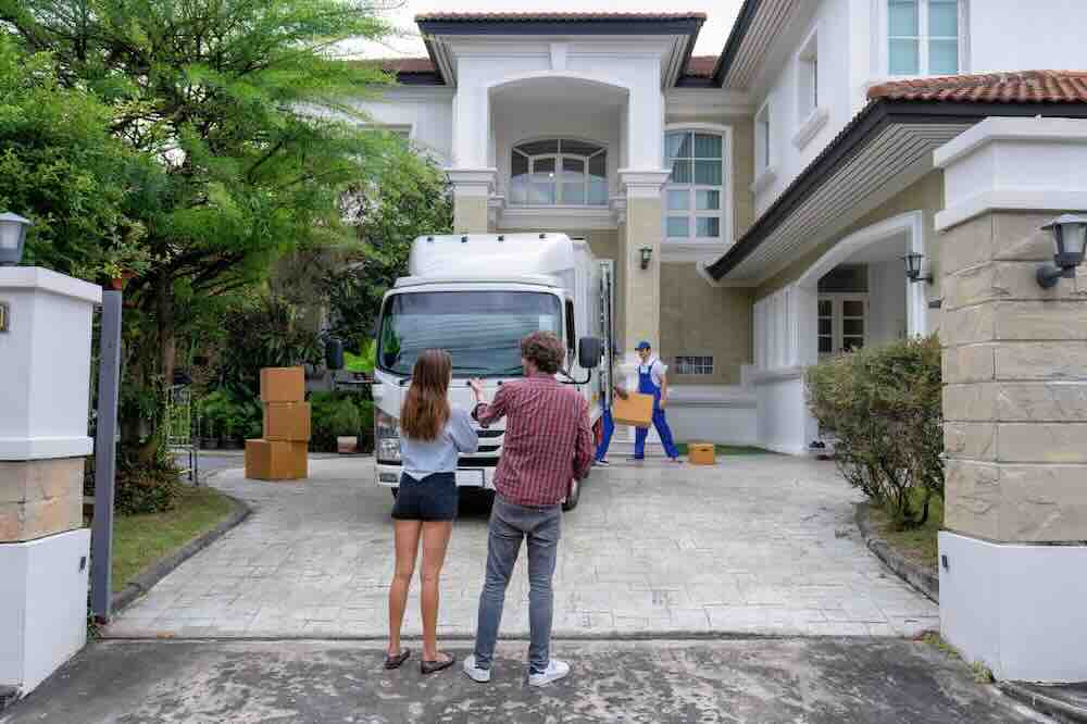 Young couple facing a moving truck from a company specializing in cross-country moves.