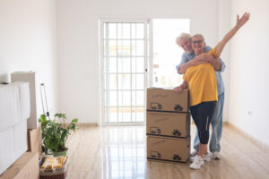 Older couple standing by boxes, following moving trends 2025 for relocating to smaller cities