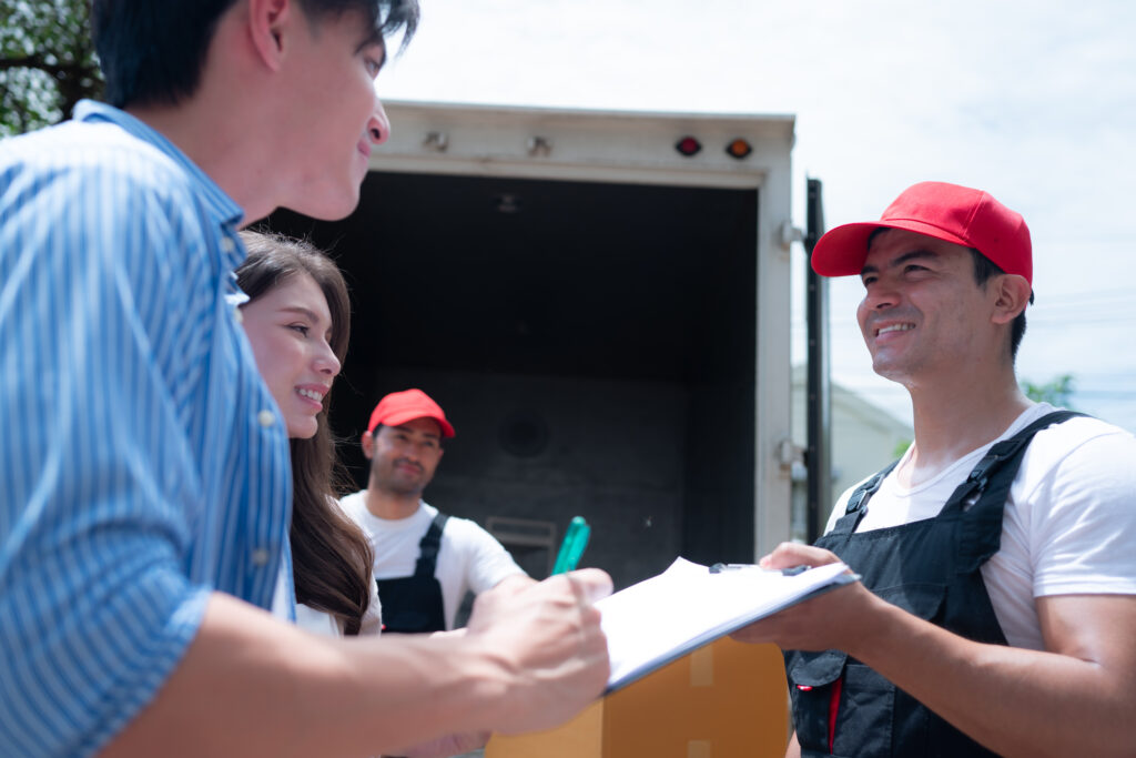 Happy couple with a professional mover with a moving checklist taking care of often overlooked moving tasks.