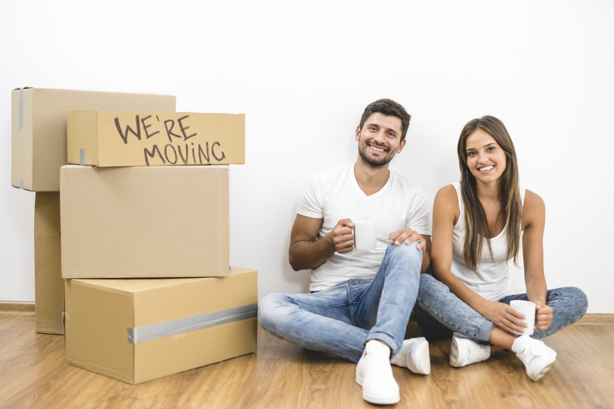 Couple seated next to boxes on the floor while following moving trends 2025.