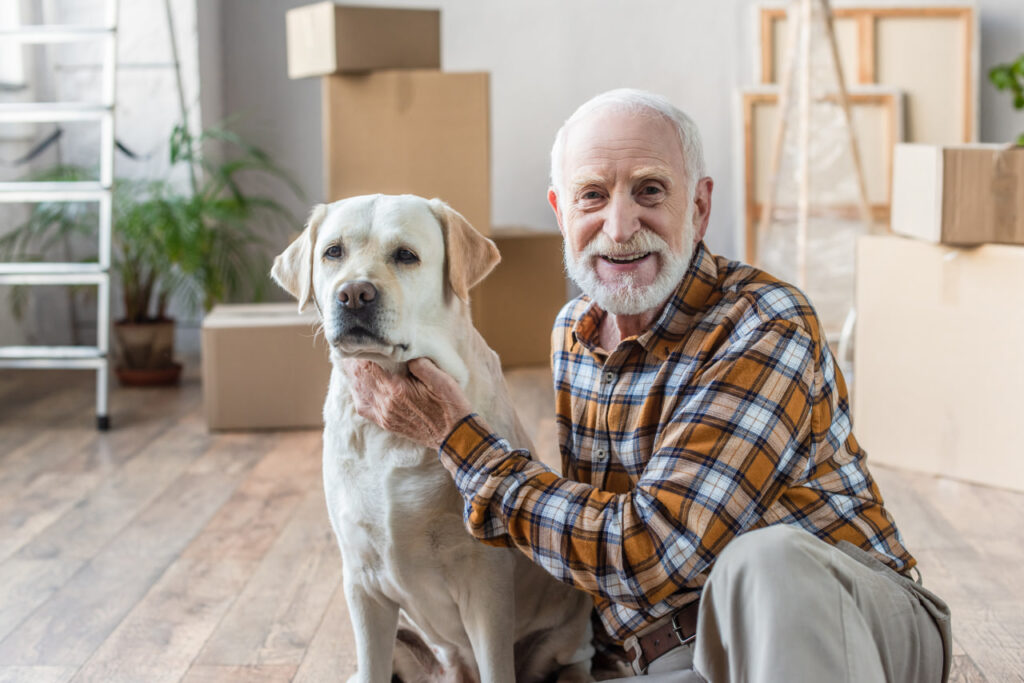 Happy older man with a dog who has followed senior relocation tips for moving with aging parents.
