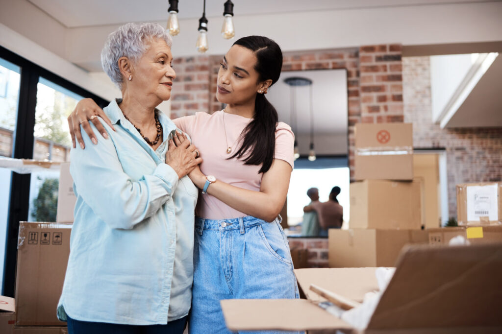 Compassionate daughter helps her mom with packing through caregiving during a move.