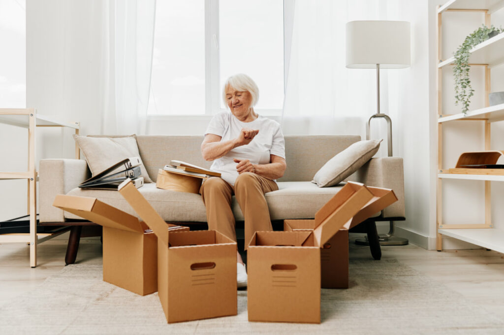 Mature woman sitting on a couch and looking through items while following senior relocation tips for moving with aging parents.
