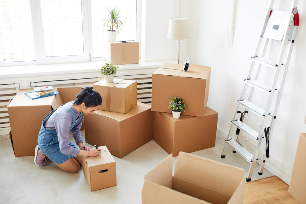 Woman labeling boxes before moving for work. 
