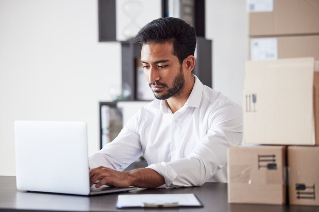 Man working on a computer, researching the best cities for workers because he’s moving for work.