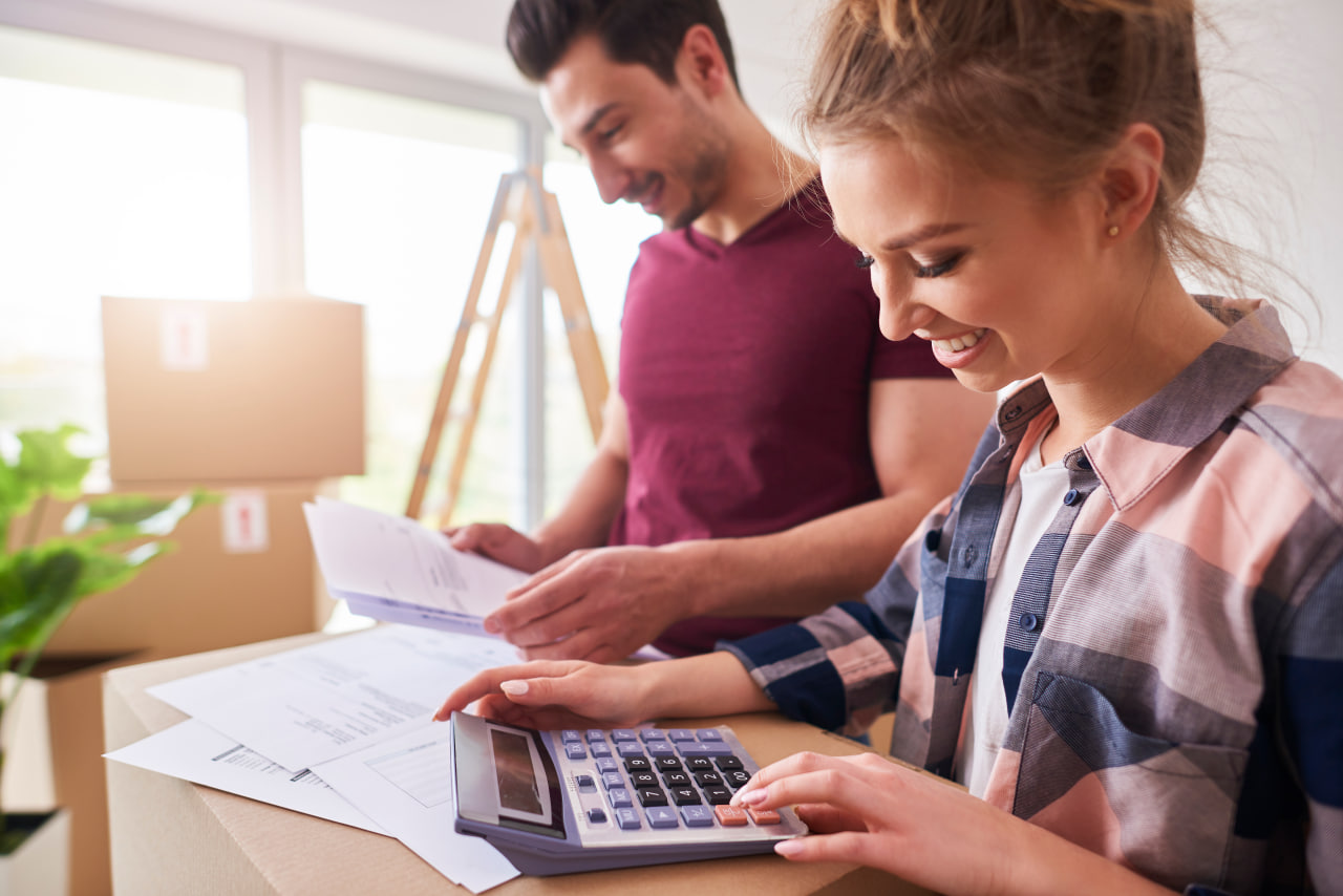 Couple with a calculator managing finances after relocation and post-move budgeting together.