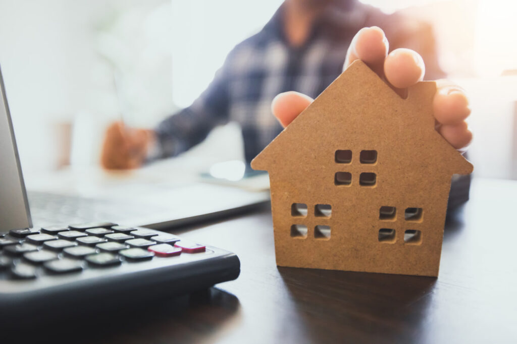 Closeup of a toy house on a keyboard representing managing finances after relocation and the cost of living after moving.